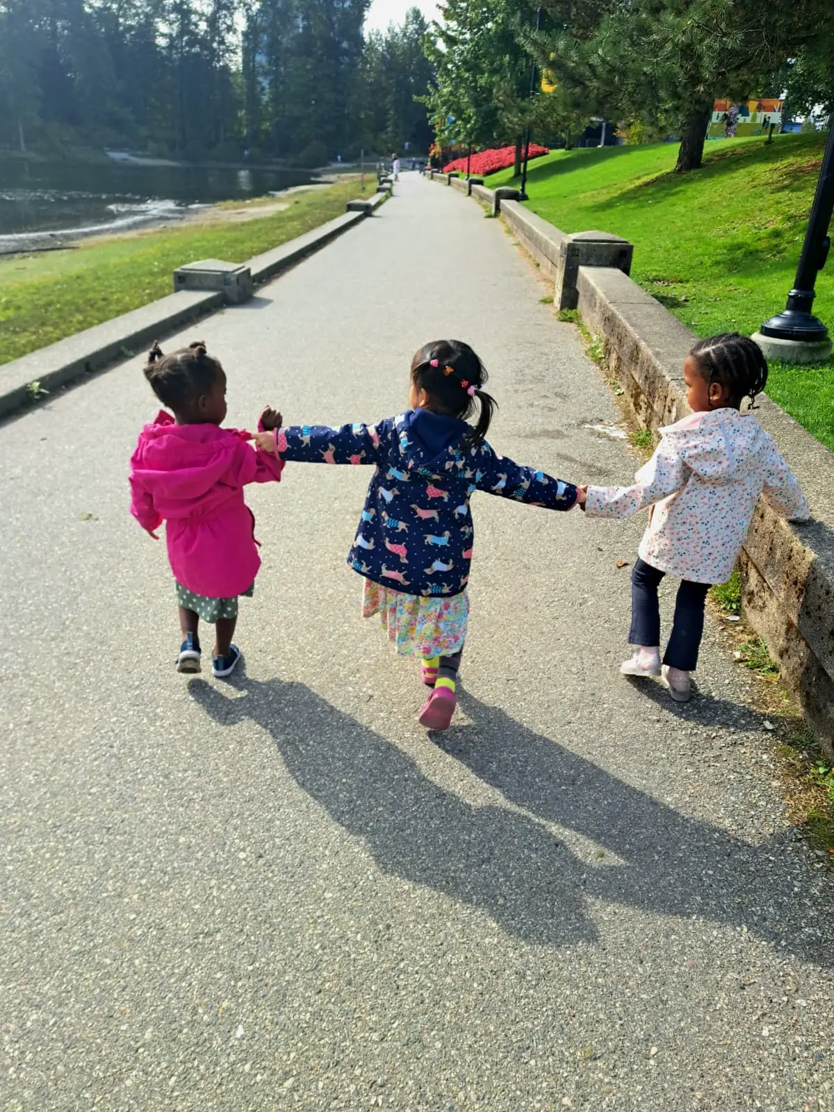 Children walking together beside a lake
