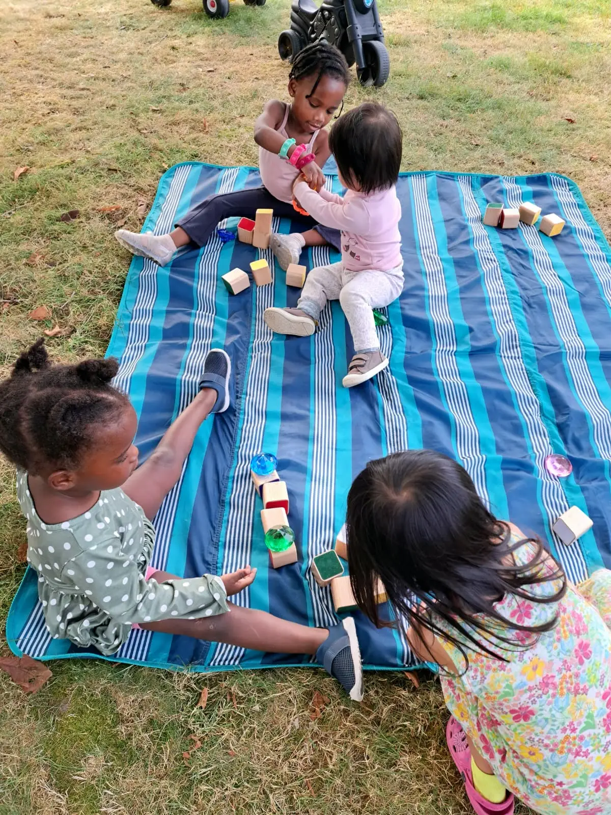 Children building with blocks outdoors on a blanket